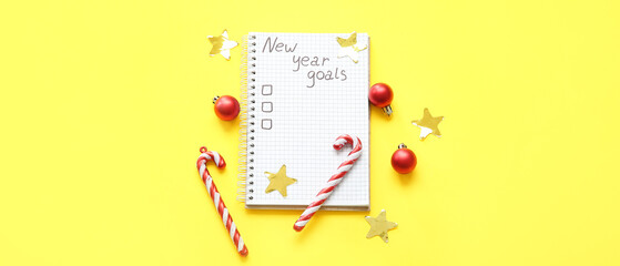 Notebook with empty to do list and Christmas decor on yellow background. New year goals