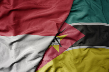big waving realistic national colorful flag of indonesia and national flag of mozambique .