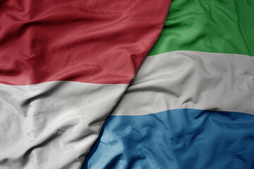 big waving realistic national colorful flag of indonesia and national flag of sierra leone .