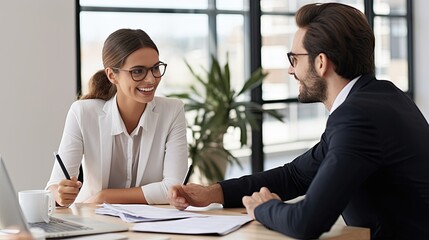 In an office environment, a man and woman are seated at a table,in a business meeting or discussion