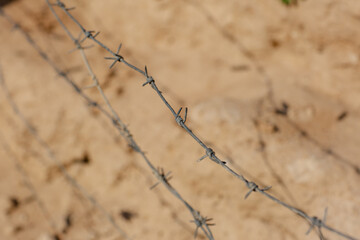Barbed wire on sand background close-up