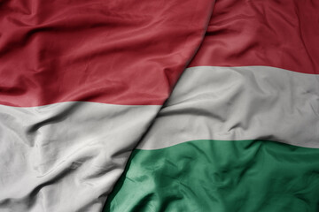 big waving realistic national colorful flag of indonesia and national flag of hungary .