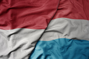 big waving realistic national colorful flag of indonesia and national flag of luxembourg .