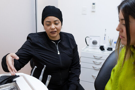 Latina Dentist Woman Sitting Talks To Patient