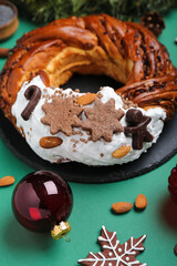 Board with tasty Christmas pastry wreath and ball on color background, closeup