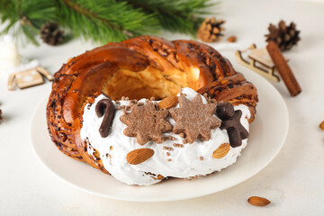 Plate with tasty Christmas pastry wreath on light background