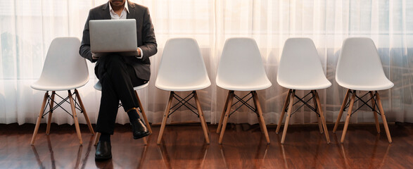 Job applicant waiting for interview in waiting room alone with empty chair on the corridor while applying on job application form. Modern employment and career seeker opportunity concept. Trailblazing