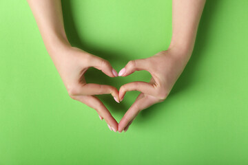 Woman making heart with her hands on green background