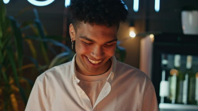 Barman guy greeting gesture at neon light bar closeup. Man hands wiping glasses
