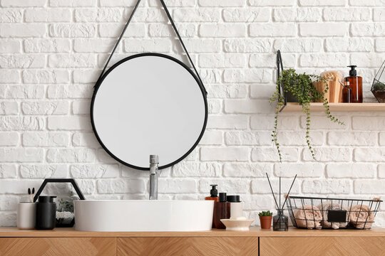 Fototapeta Sink bowl and bath accessories on wooden cabinet near white brick wall