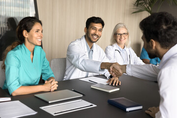 Positive confident chief physician shaking hands with partners, sponsor, hiring new doctor after...