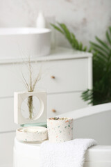 Holders with candles and towel on bathtub in bathroom, closeup