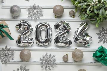 Figure 2024 made of foil balloons with Christmas balls, snowflakes and mistletoe branch on white background