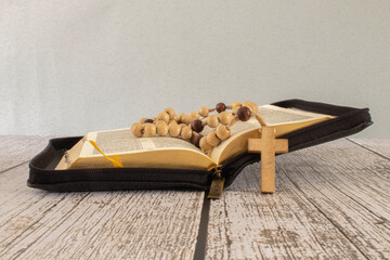 Bible crucifix and beads on a brown wooden table. Beautiful background. Religion concept.