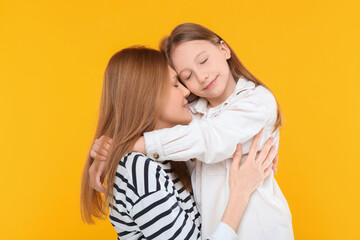Portrait of happy mother and her cute daughter on orange background