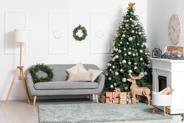 Interior of living room with Christmas tree, grey sofa, gift boxes and fireplace