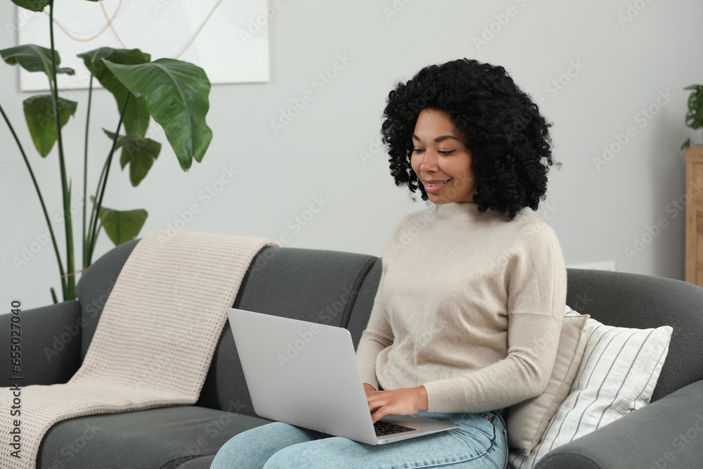 Poster happy young woman using laptop on sofa indoors. space for text