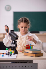 Small girl studying chemistry in the classroom