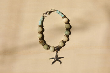 Beautiful bracelet with different gemstones on beige background, top view