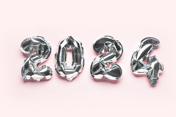 Silver foil balloons number 2024 on pink background. New year concept.