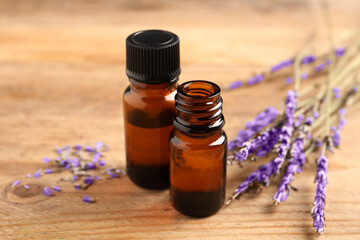 Fototapeta na wymiar Essential oil and lavender flowers on wooden table, closeup