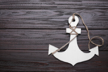 White anchor with hemp rope on dark wooden table, top view. Space for text