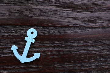 Anchor figure on dark wooden table, top view. Space for text