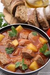 Delicious goulash in saucepan on table, closeup