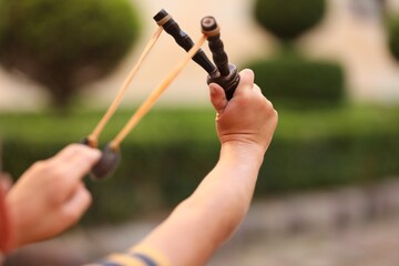 Little boy playing with slingshot outdoors, closeup