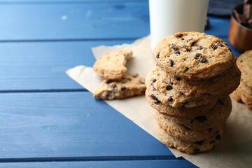 Tasty chocolate chip cookies and glass of milk on blue wooden table, closeup. Space for text