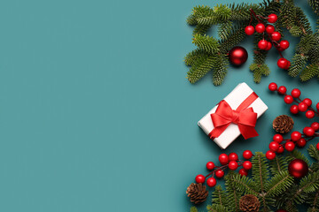 Christmas tree branches with gift box, balls and rowan on blue background