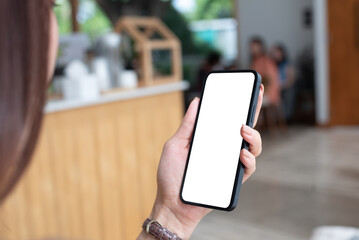 cell phone blank white screen mockup. Woman hand holding, using mobile phone at coffee shop background empty space for advertise, mobile app, social media marketing, business and technology