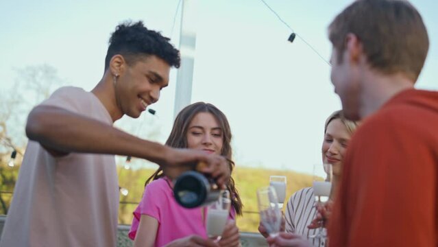 African guy pouring champagne at rooftop corporate event closeup. Party concept