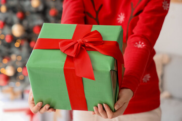 Woman with present at home on Christmas eve, closeup