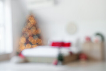 Blurred view of festive bedroom with comfortable bed and Christmas tree