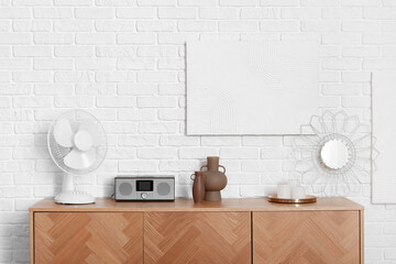 Modern fan and radio on wooden cabinet in interior of light living room