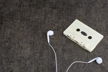 top view of white cassette tape and white earphones on wooden table
