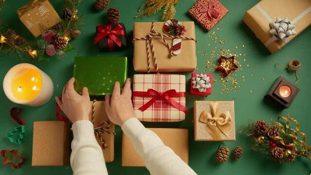 Happy New Year, Merry Christmas gift boxes. Male hands placing many colorful presents wrapped in red ribbons on green table with decorations. Christmas background, beautiful gift boxes RED camera 4K