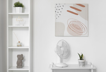 Electric fan with houseplant on shelf in interior of light room