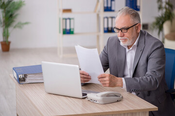 Old male employee working in the office