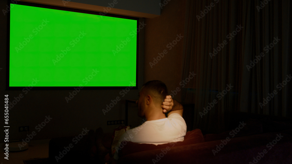 Poster viewing on a projector in a closed room. media. a man looking into a green screen that is shown on a