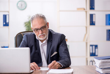 Fototapeta premium Old male employee working in the office