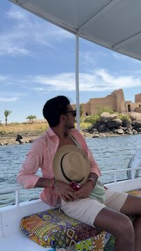 person sitting on a boat in egyptian nile in front of isis temple in philae aswan