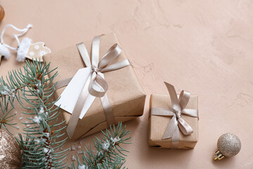 Fototapeta na wymiar Christmas tree branches and gift boxes on beige background