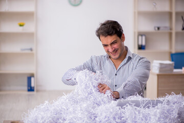 Young male employee and a lot of cut papers in the office