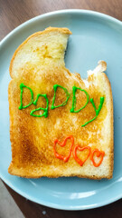 Bread toast with butter, with drawing Daddy and three hearts in morning for breakfast in homemade family meal