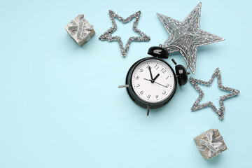 Composition with alarm clock, Christmas decorations and gift boxes on color background
