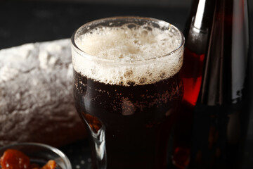 Glass and bottle of tasty kvass on black background