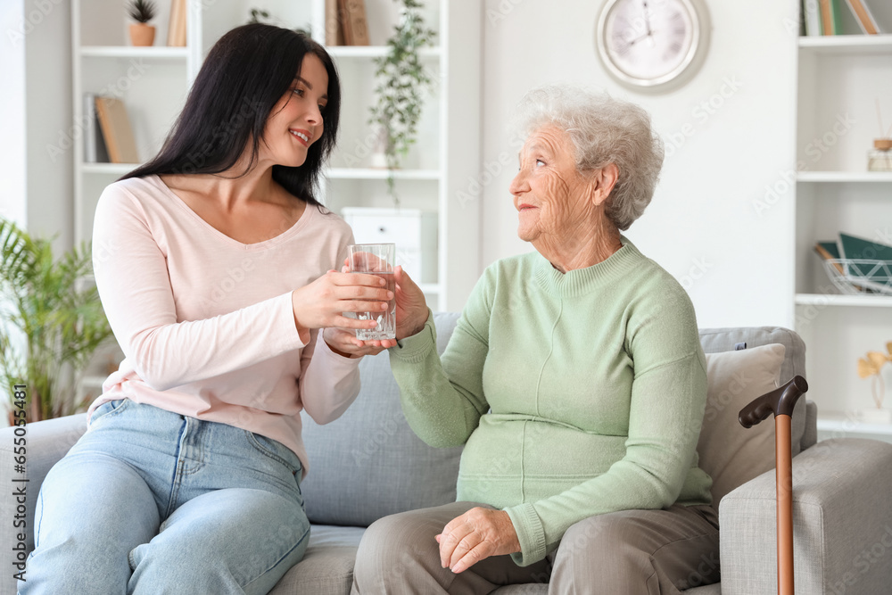 Sticker Senior woman taking glass of water from her daughter at home