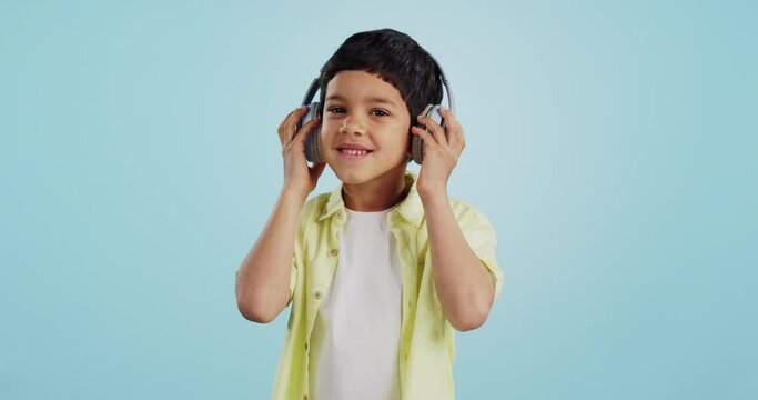 Kid, dancing and listening to music in studio with smile on blue background in mockup for fun, promotion and summer. Youth, boy or person with headphones for app, streaming or game on social media